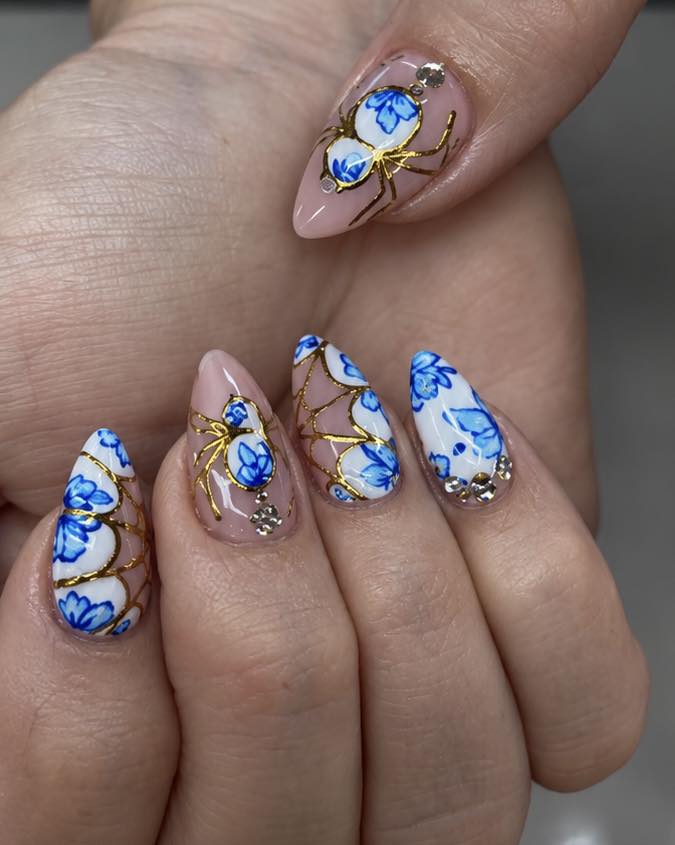 Blue porcelain nail art with gold spiderweb accents